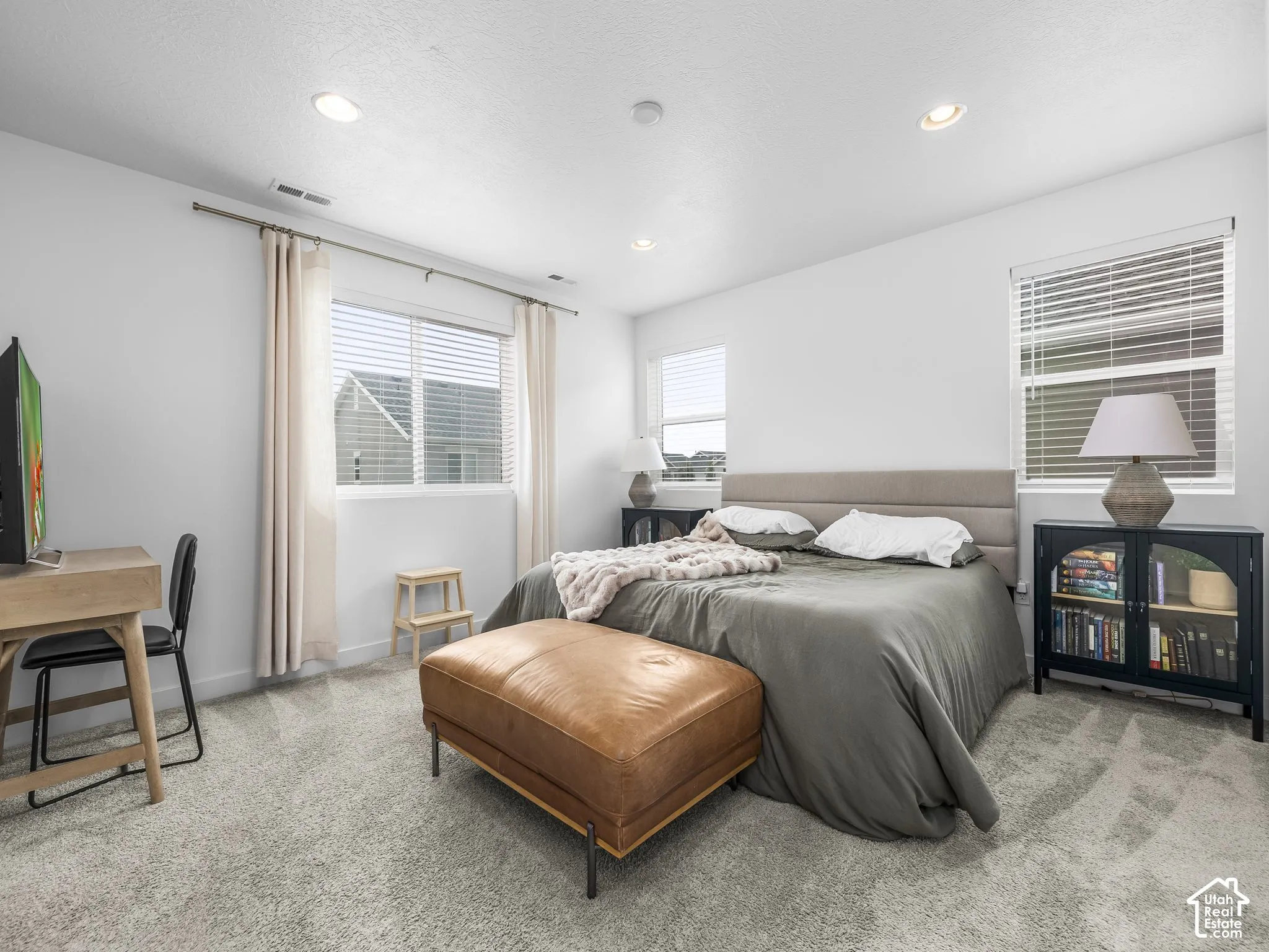 Recessed ceiling lighting, light gray wall paint, two windows with blinds and curtain rods, and gray carpet flooring