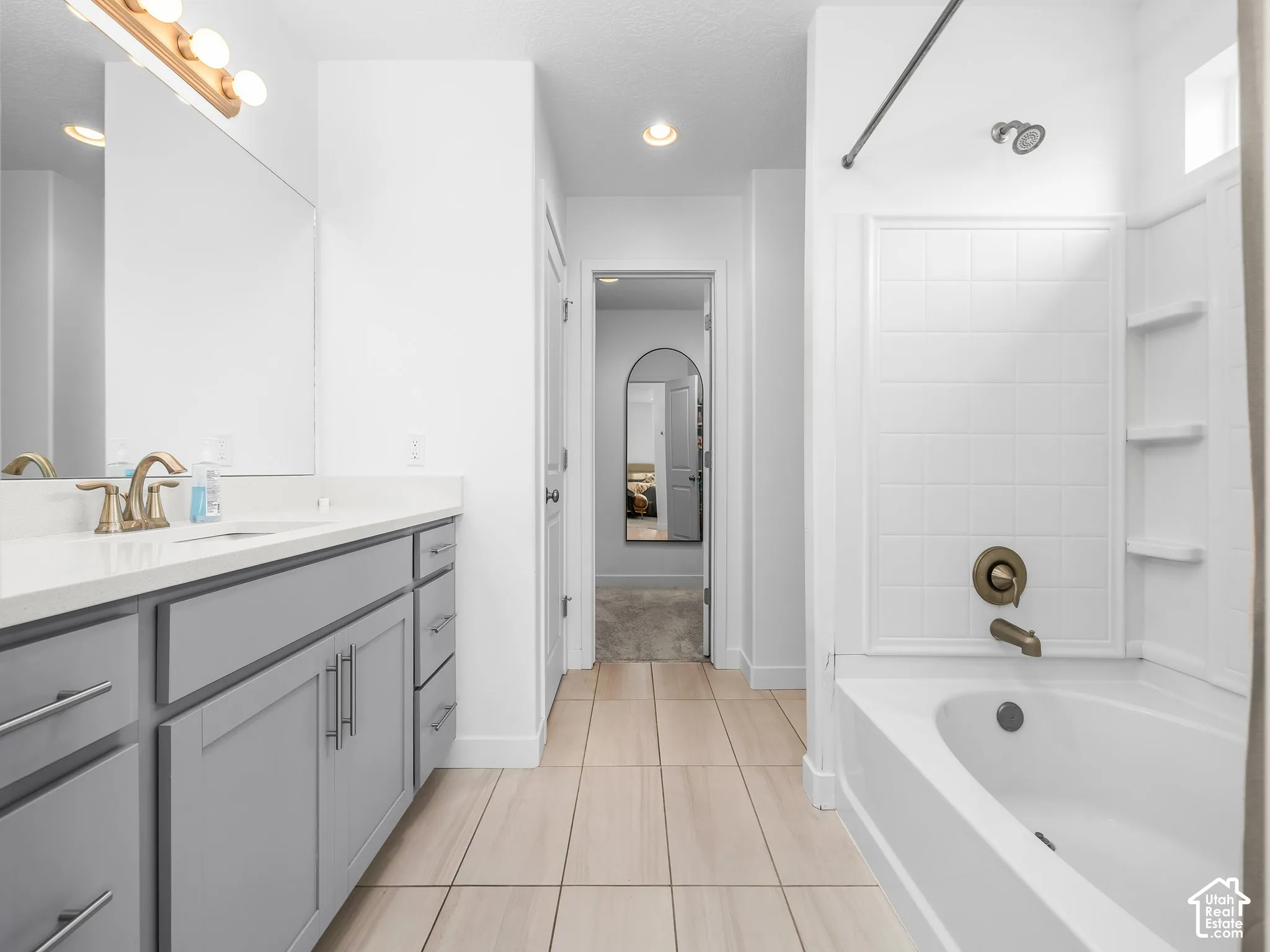 Vanity with gray cabinetry, white countertop, and brushed brass fixtures