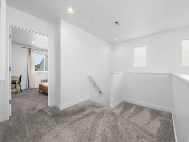 Carpeted landing with recessed lighting, white walls, and white trim