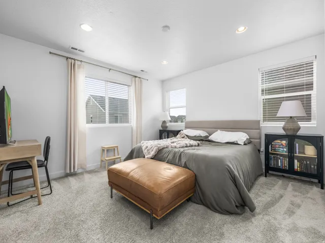 Recessed ceiling lighting, light gray wall paint, two windows with blinds and curtain rods, and gray carpet flooring