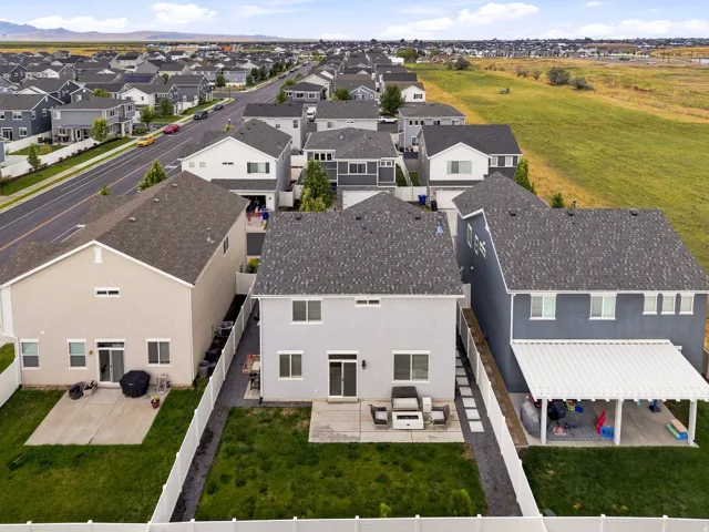 Rear exterior featuring a patio, manicured lawn, and white fencing