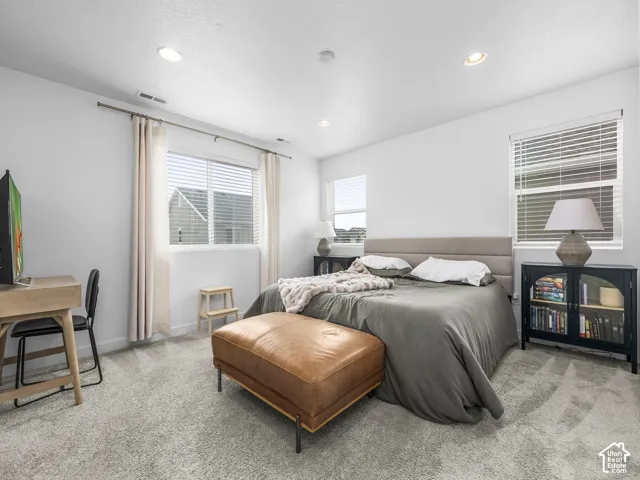 Recessed ceiling lighting, light gray wall paint, two windows with blinds and curtain rods, and gray carpet flooring