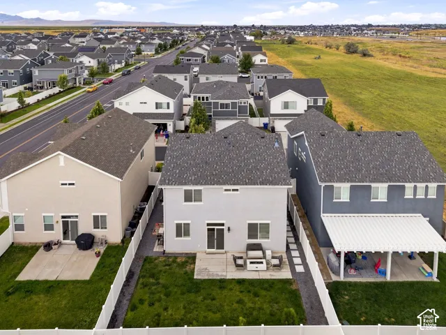 Rear exterior featuring a patio, manicured lawn, and white fencing