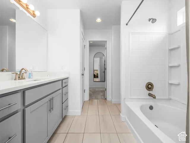 Vanity with gray cabinetry, white countertop, and brushed brass fixtures