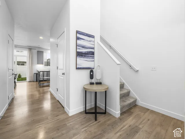 Bright hallway with wood-finish flooring, white painted walls, and recessed ceiling lighting