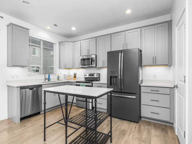 Modern kitchen featuring gray cabinetry, light countertops, wood-finish flooring, recessed lighting, and stainless steel appliances