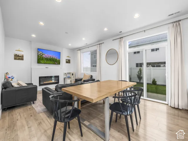 Open-concept living space featuring wood-finish flooring, recessed lighting, and a modern fireplace