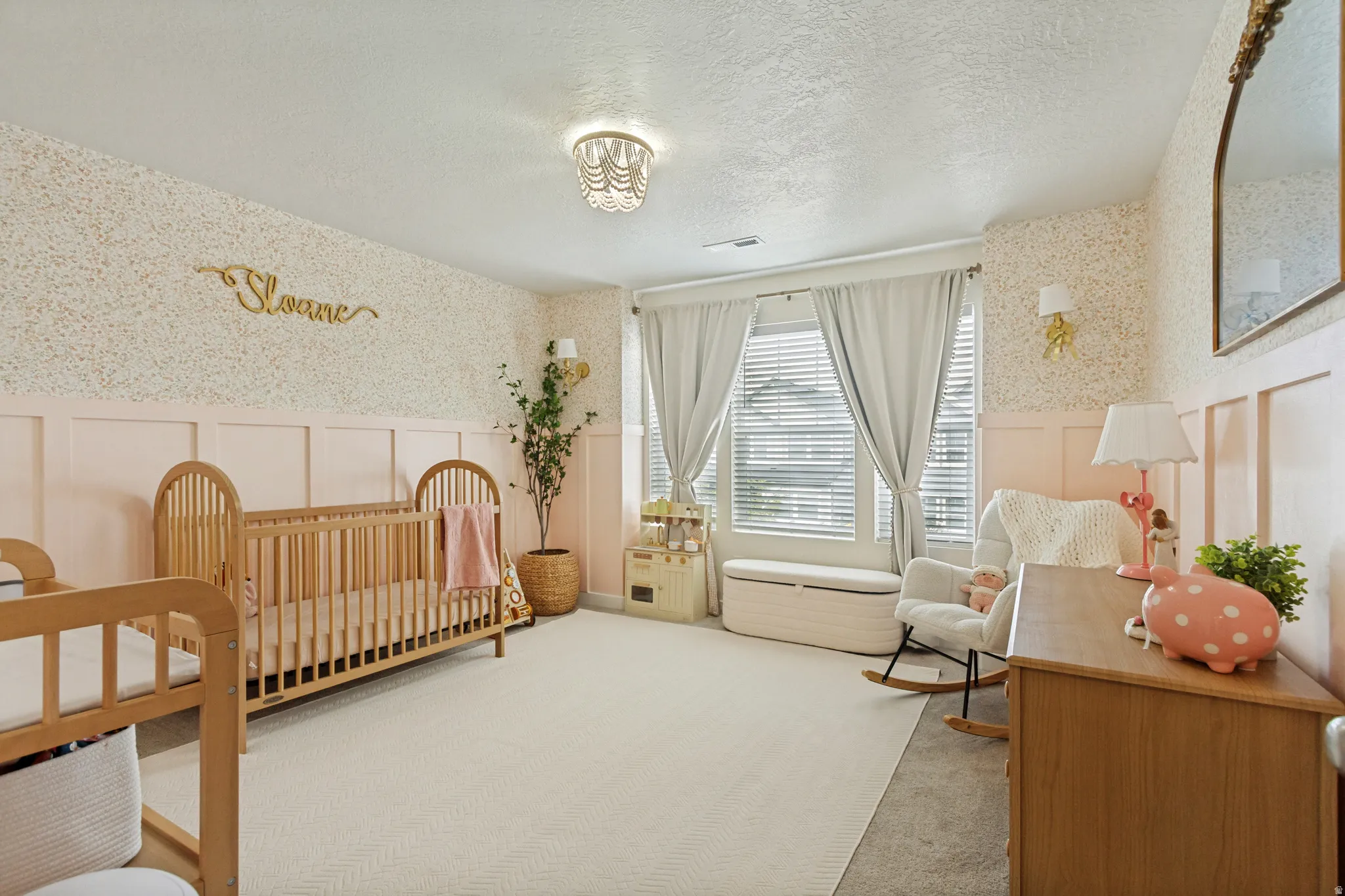 Textured wallpaper accent wall, wainscoting detail, white window blinds, recessed lighting, and a decorative ceiling fixture
