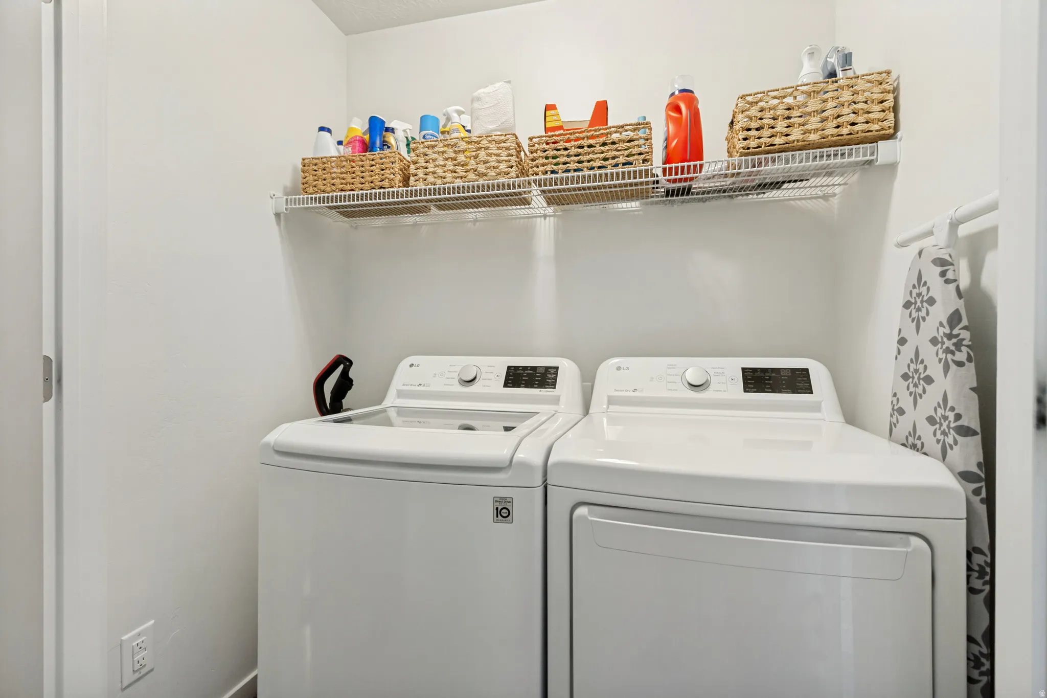 Laundry area featuring a built-in wire shelving unit and white walls