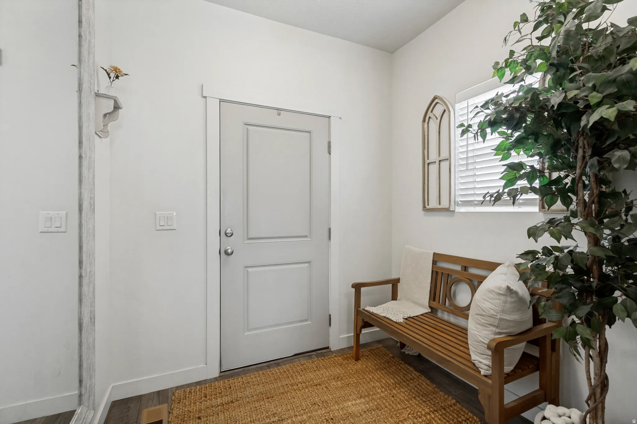Entryway with a solid panel door, wood-finish flooring, and a window with blinds