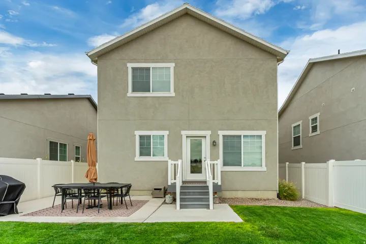 Rear stucco exterior with white trim windows and a glass-paneled door
