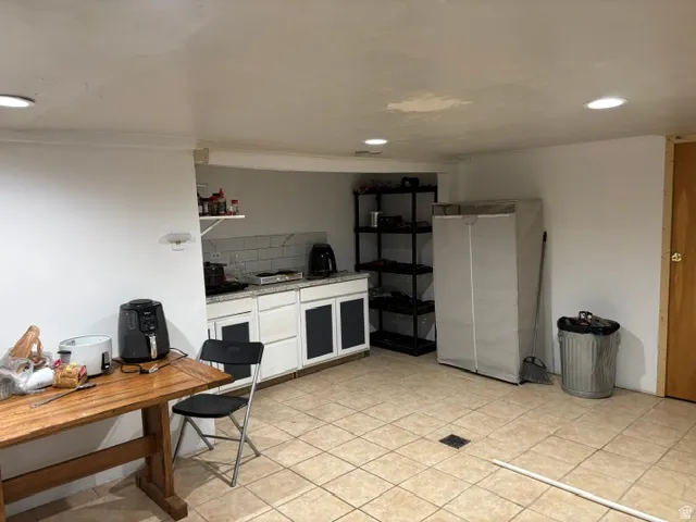 Recessed ceiling lighting, tiled flooring, built-in lower cabinetry with a countertop, subway tile backsplash, and a wooden door