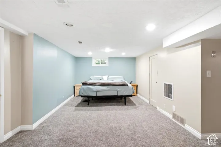 Room featuring light blue accent wall, neutral tone walls, recessed lighting, white trim, and gray carpet flooring