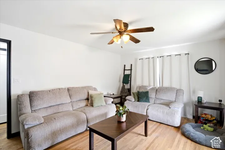 Wood-finish flooring throughout, bright white walls, and a ceiling fan with integrated lighting