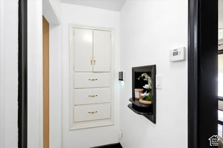 Built-in white cabinetry with gold-tone hardware, recessed wall niche, and modern thermostat