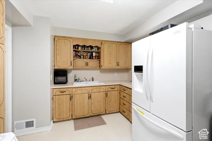 Light wood-finish cabinetry, white countertop, and white flooring