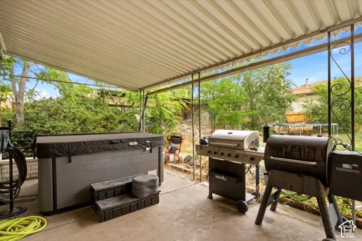 Covered outdoor entertaining space featuring a corrugated metal roof, concrete flooring, and expansive open-air design