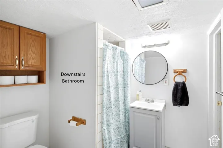 White bathroom featuring a vanity with an integrated sink, a circular mirror, and overhead lighting