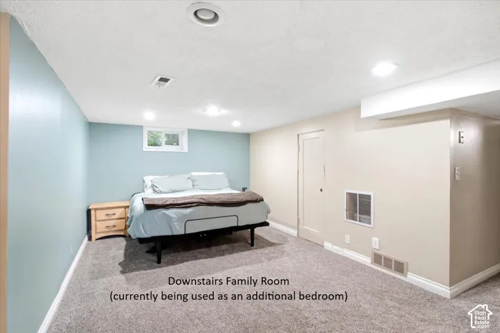 Recessed lighting, carpet flooring, a window, and a white door with a handle