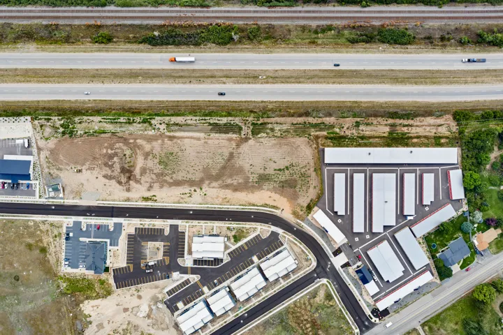Expansive development site featuring existing commercial structures, paved roadways, and a gravel lot