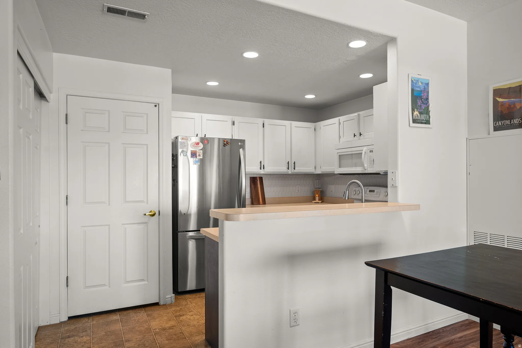 Kitchen featuring white cabinetry, stainless steel refrigerator, white microwave, and wood-finish countertops