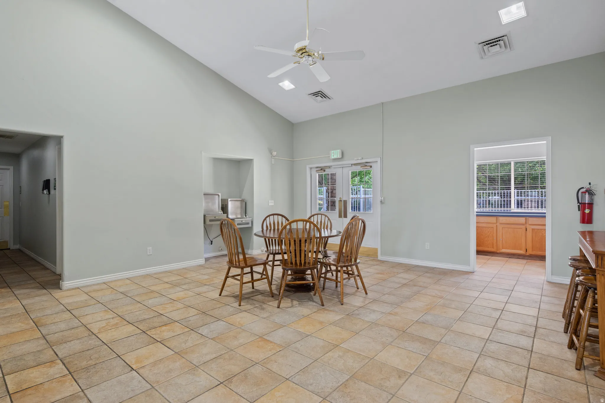 Vaulted ceiling, ceiling fan, tile flooring, and double-door exterior access