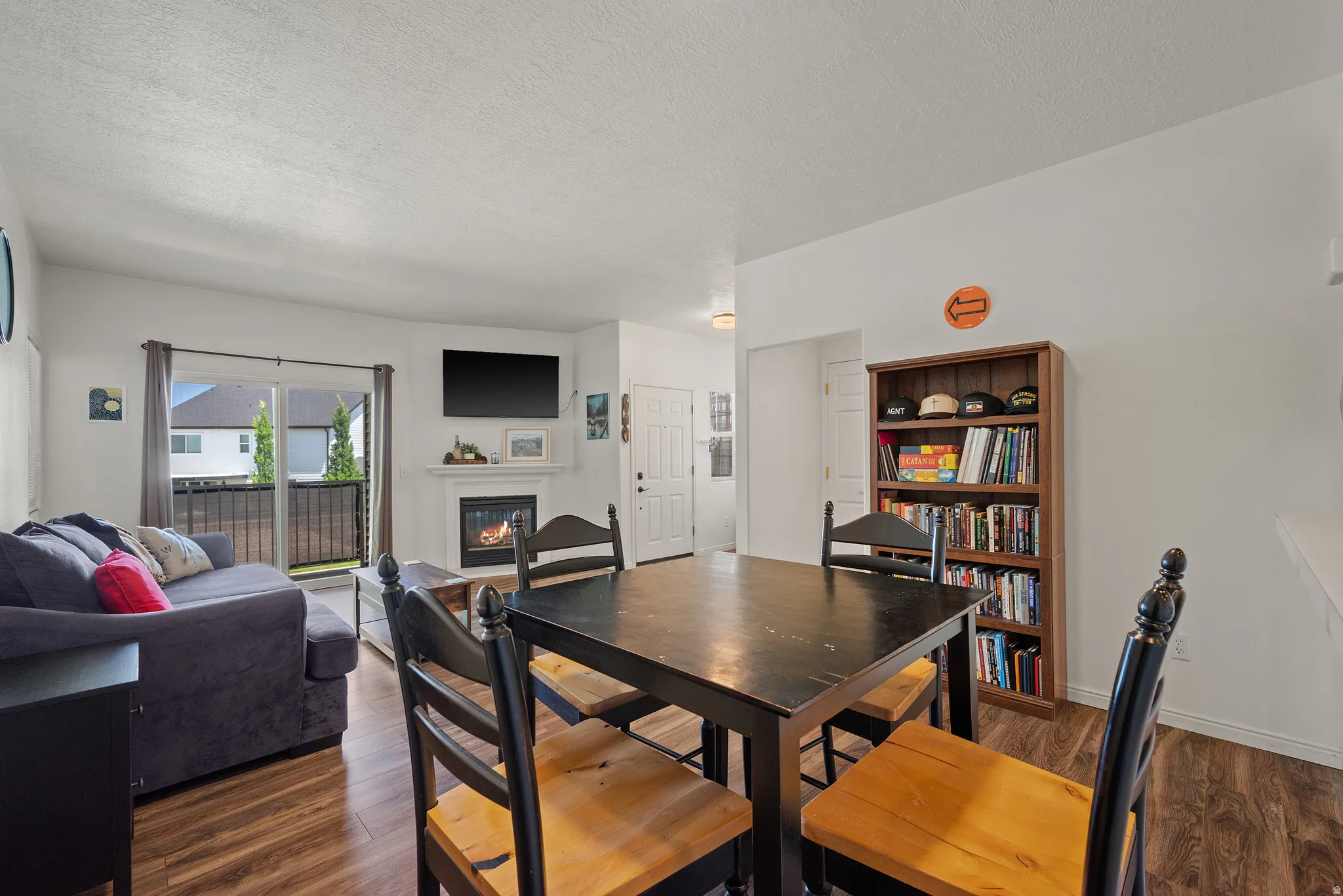 Wood-finish flooring throughout, with a built-in fireplace featuring a mantel, and a sliding glass door opening to an exterior space