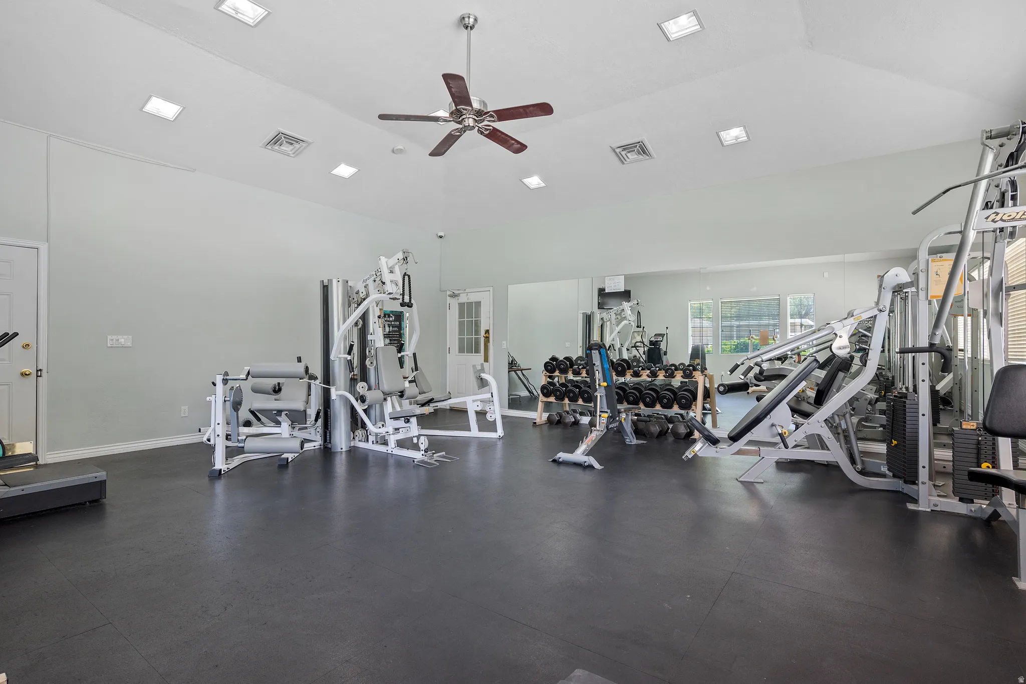 Vaulted ceiling with recessed lighting and a ceiling fan, mirrored wall, and black mat flooring