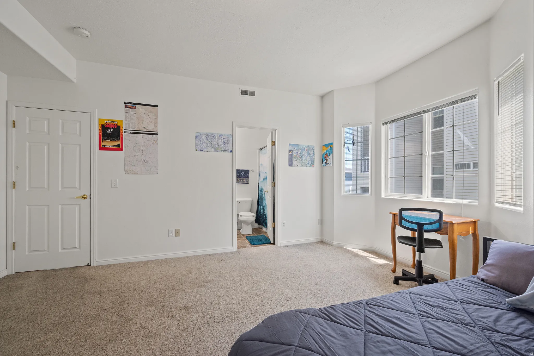 Carpeted room with multiple windows, an interior door, and an attached bathroom