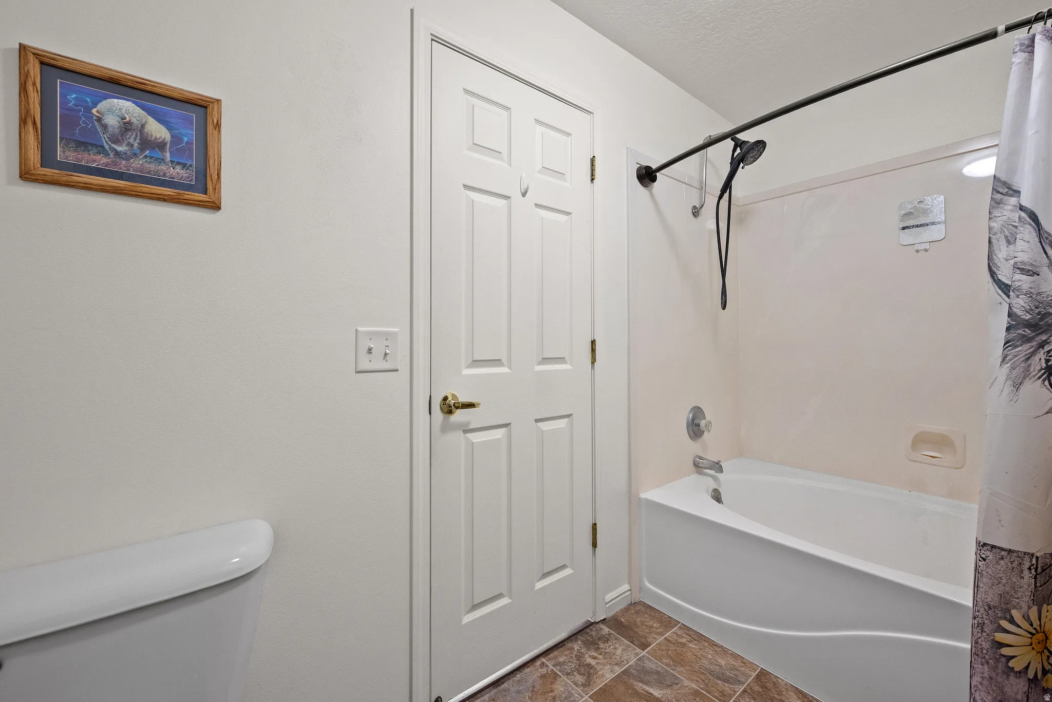 Enclosed bathtub with a wall-mounted shower fixture, complemented by tiled flooring