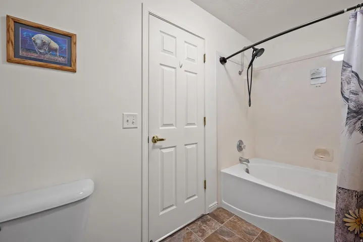 Enclosed bathtub with a wall-mounted shower fixture, complemented by tiled flooring