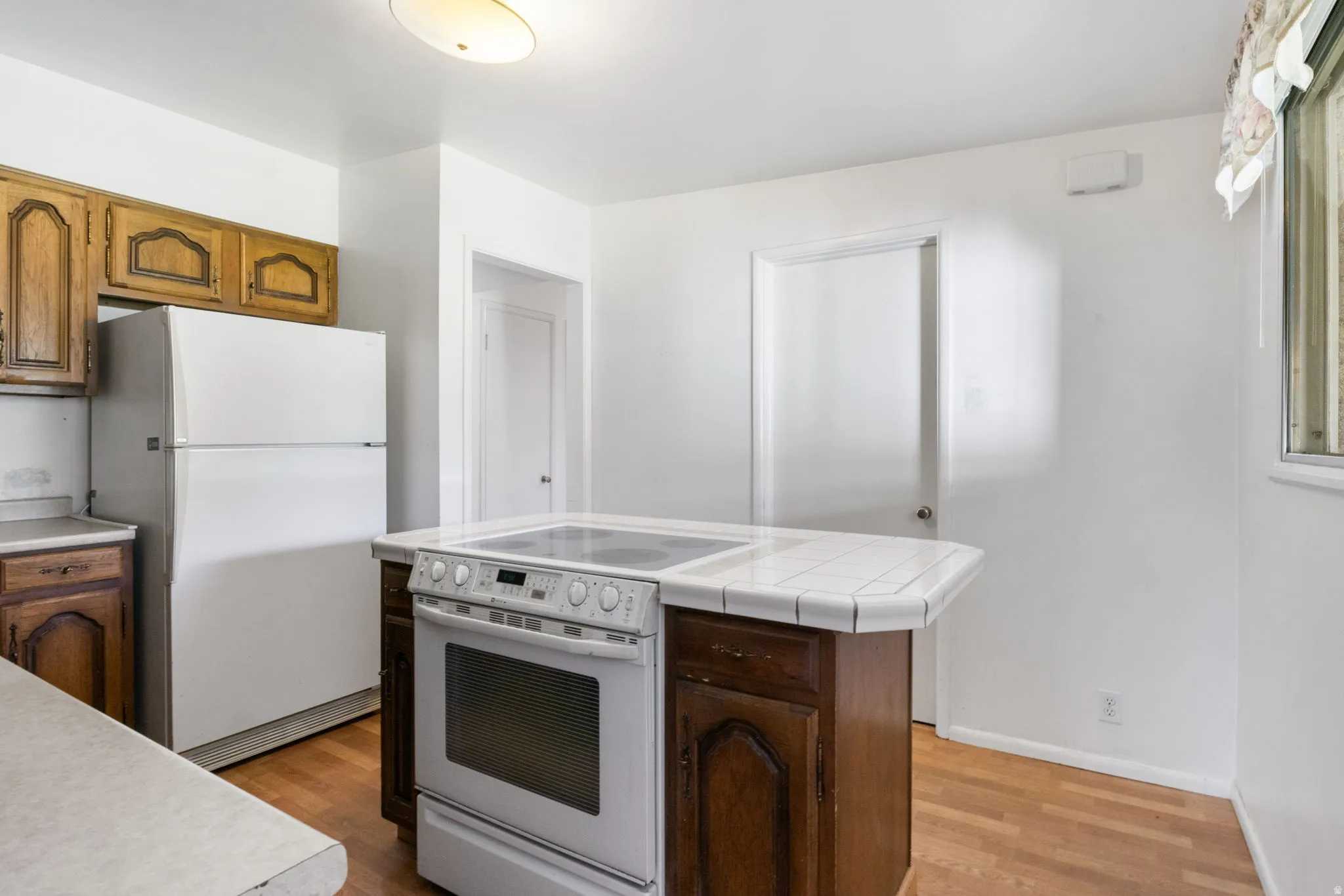 Kitchen area featuring wood-finish flooring, white walls, and wood cabinetry