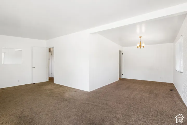 Spacious interior with neutral carpeting, white walls, and a classic chandelier
