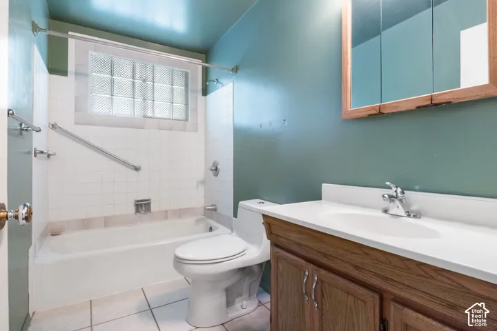 Bathroom featuring a built-in tub, white tile surround, glass block window, wood-finish vanity with an integrated sink, and a mirrored medicine cabinet