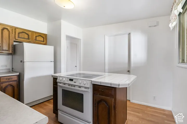 Kitchen area featuring wood-finish flooring, white walls, and wood cabinetry