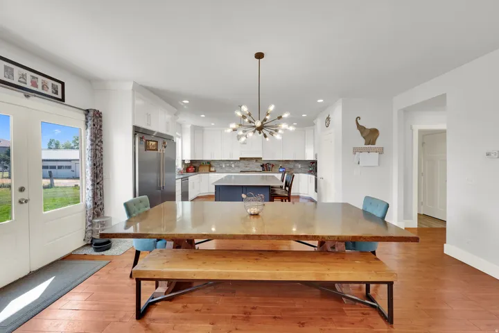 Kitchen with white shaker cabinetry, stainless steel refrigerator, dark gray island, and wood-finish flooring
