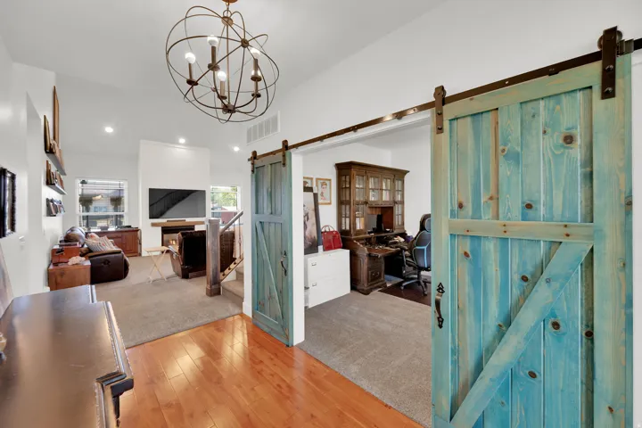 Vaulted ceilings with an orbital chandelier, wood-finish flooring, recessed lighting, and a fireplace with a wood mantle