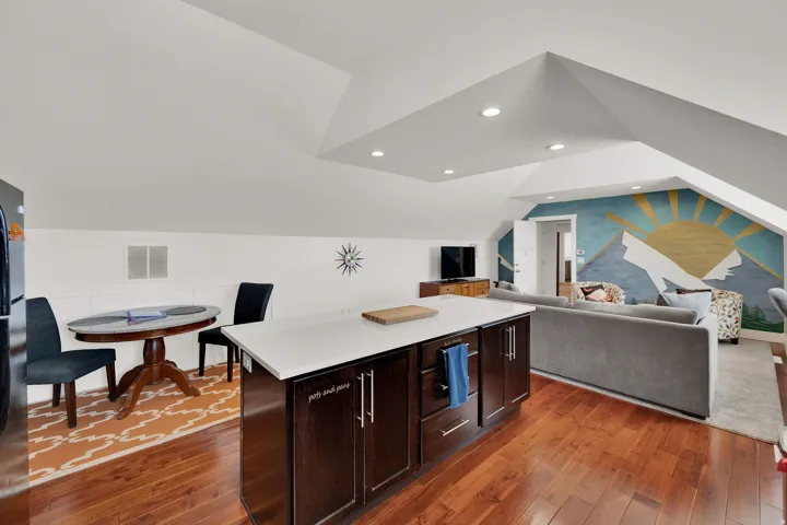 Hardwood flooring throughout, recessed lighting, white countertops, dark wood cabinetry, and an open-concept layout