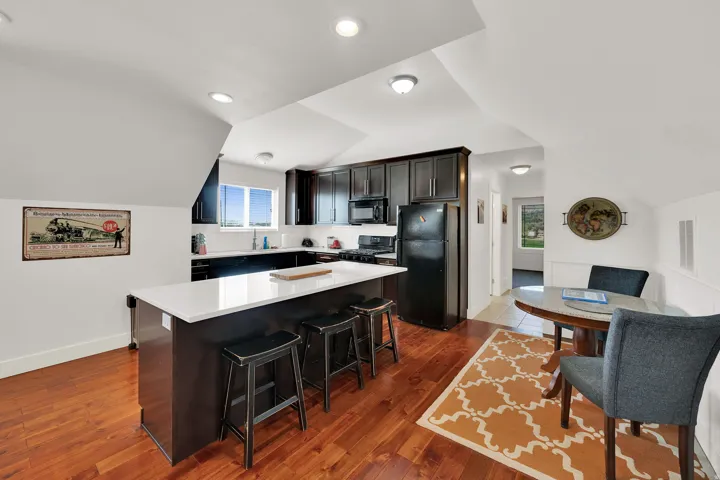 Kitchen featuring rich wood-finish flooring, dark cabinetry, and a central island with a light-colored countertop