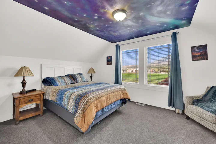 White walls featuring a sloped ceiling with a decorative ceiling mural