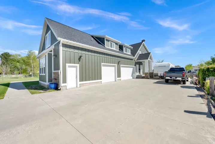 Modern farmhouse with board-and-batten siding, gabled roofline with multiple peaks, and dormer windows