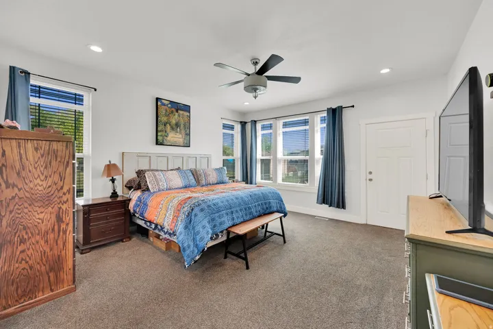 Recessed lighting, ceiling fan, multiple windows with blinds, white trim, and a paneled door