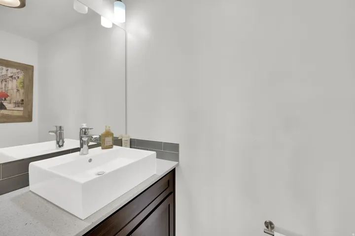 Modern rectangular vessel sink atop a solid surface countertop with a single-handle chrome faucet