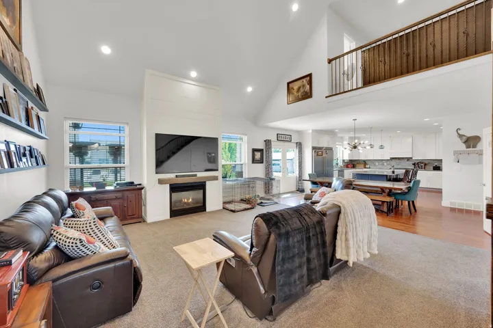 Vaulted ceilings, a gas fireplace with wood mantel, and an upper-level balcony with wood railing