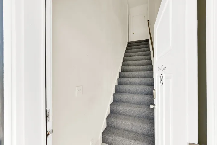 Staircase featuring grey carpeting and a wooden handrail