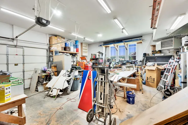Garage space with an overhead door, multiple fluorescent light fixtures, and upper windows