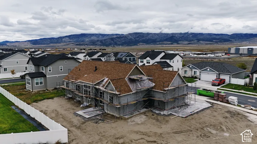 New construction home featuring a multi-gabled asphalt shingle roof and mountain backdrop