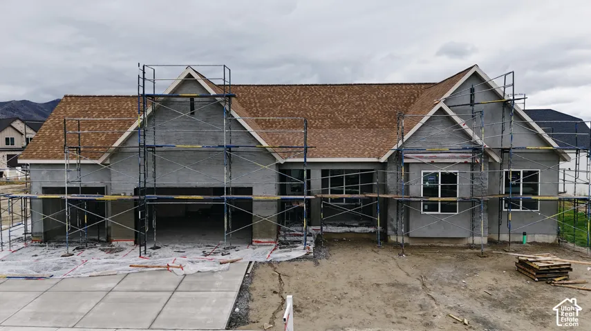 Multi-gabled exterior with shingled roof, stucco finish, multi-pane windows, and a concrete driveway