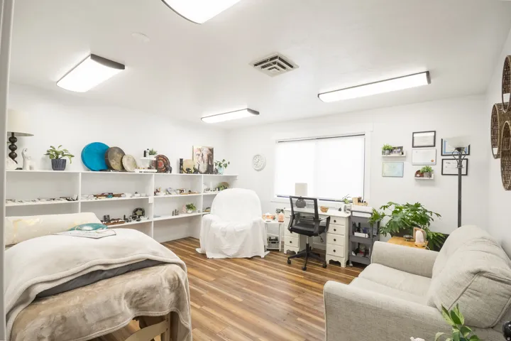 Brightly lit room featuring wood-finish flooring, built-in shelving, and multiple windows with roller shades