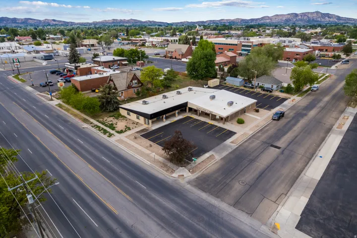 L-shaped commercial building featuring a flat roof and a paved parking area